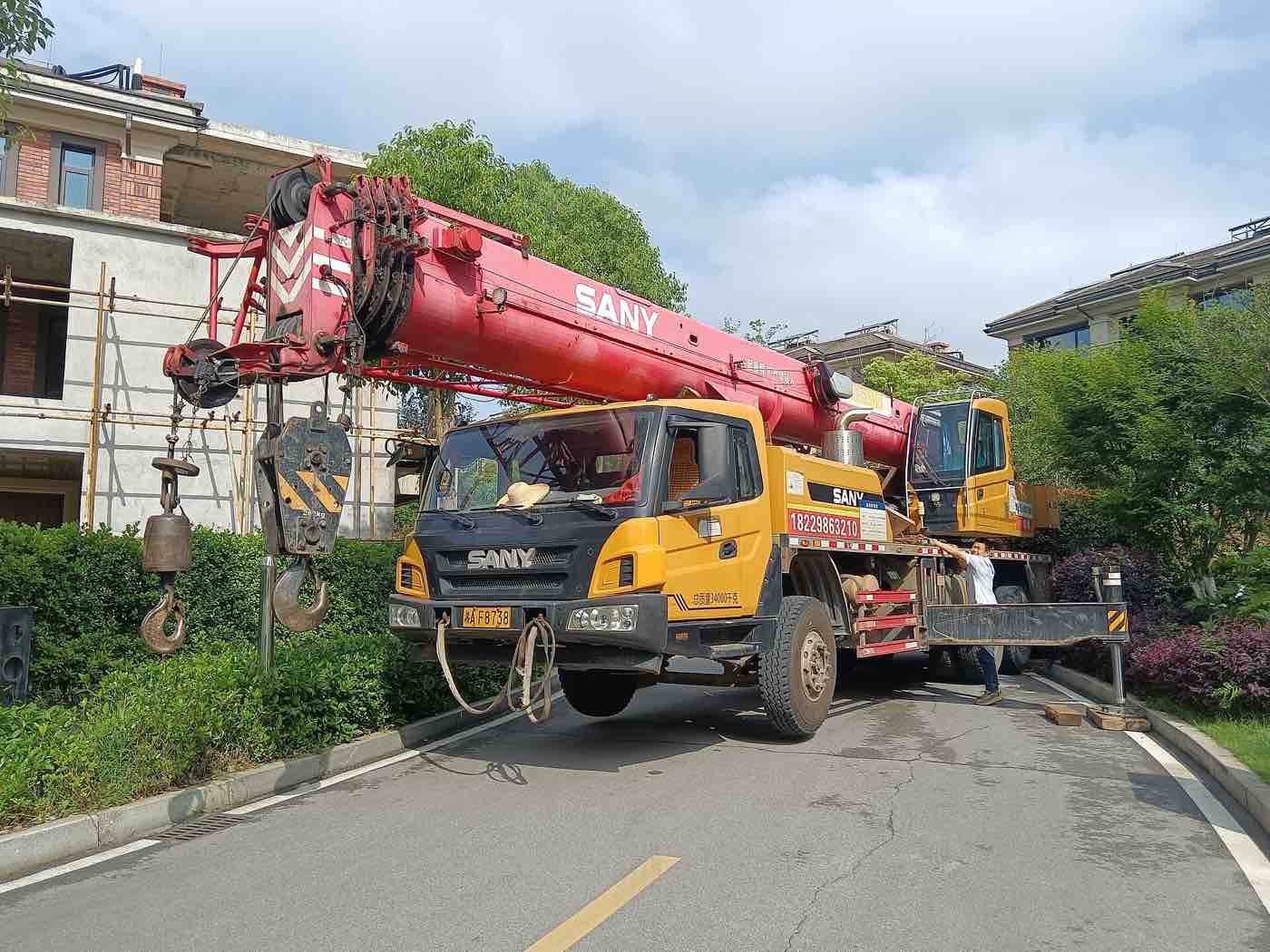 SANY STC series mobile truck crane with red multi-section U-shape telescopic boom, boom-head sheaves, anti-two-block A2B counterweight switch, 4-sheave main hook block, auxiliary ball hook, yellow carrier cab, and extended H-type outriggers.